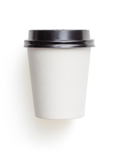 A plain white disposable coffee cup with a black plastic lid is centered against a white background. The cup has a simple, sleek design, showcasing a minimalist aesthetic.