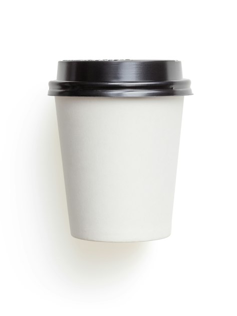A white paper coffee cup with black lid on a white surface, representing the paper versus plastic cup comparison