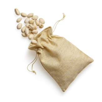 A handful of mixed nuts and almonds spilling from a burlap sack onto a natural linen cloth