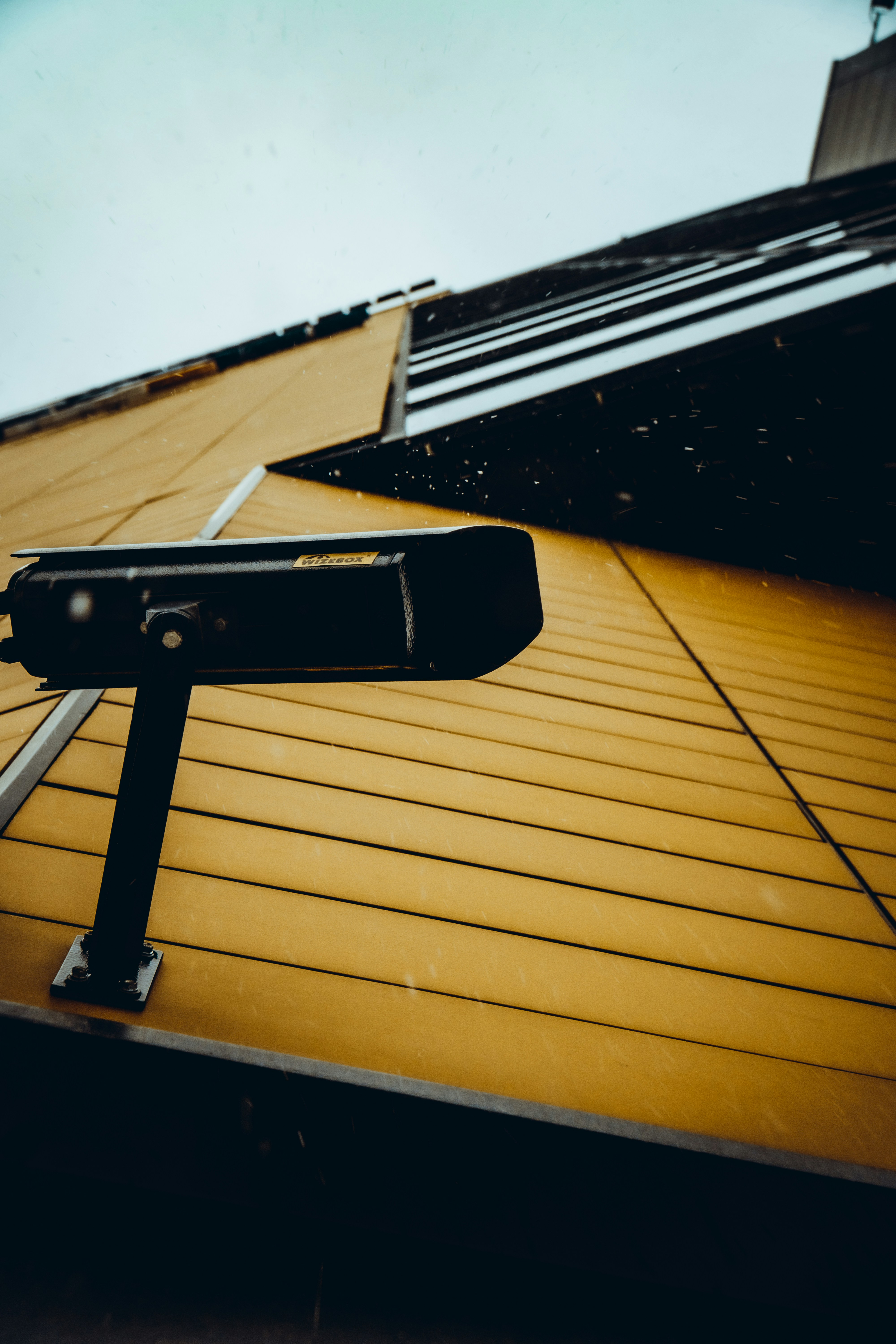 Security camera mounted on wall exterior, night surveillance, dark dramatic environment