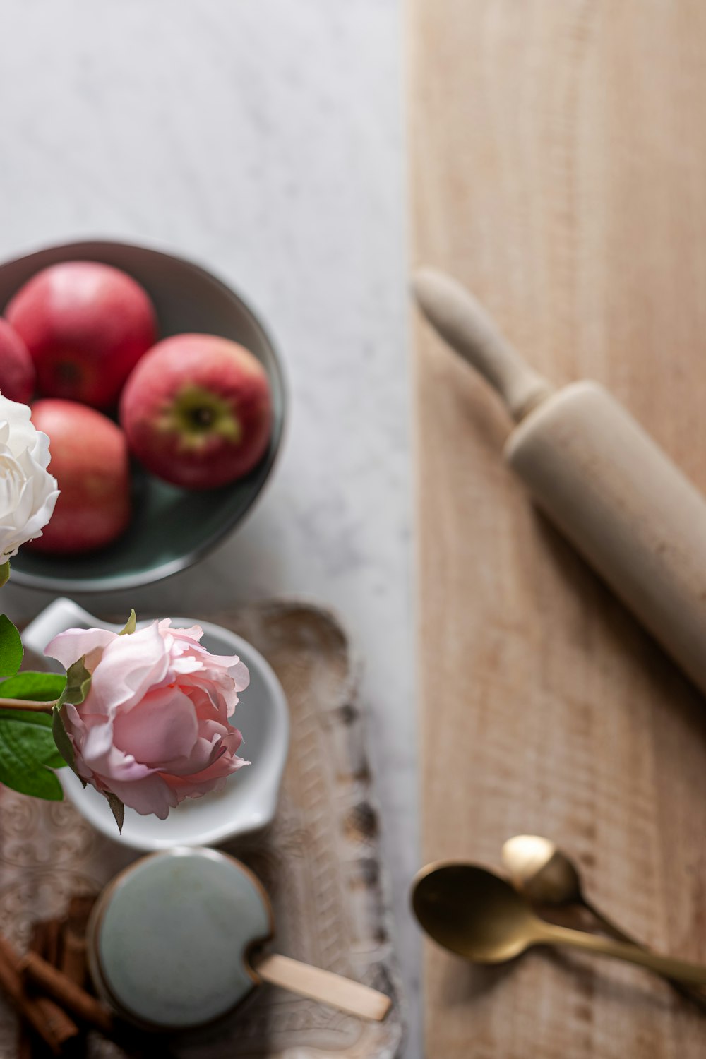 white and pink rose bouquet beside brown wooden rolling pin