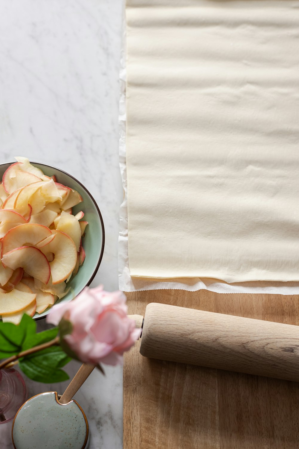 Rodillo de madera marrón sobre plato de cerámica floral blanca y verde