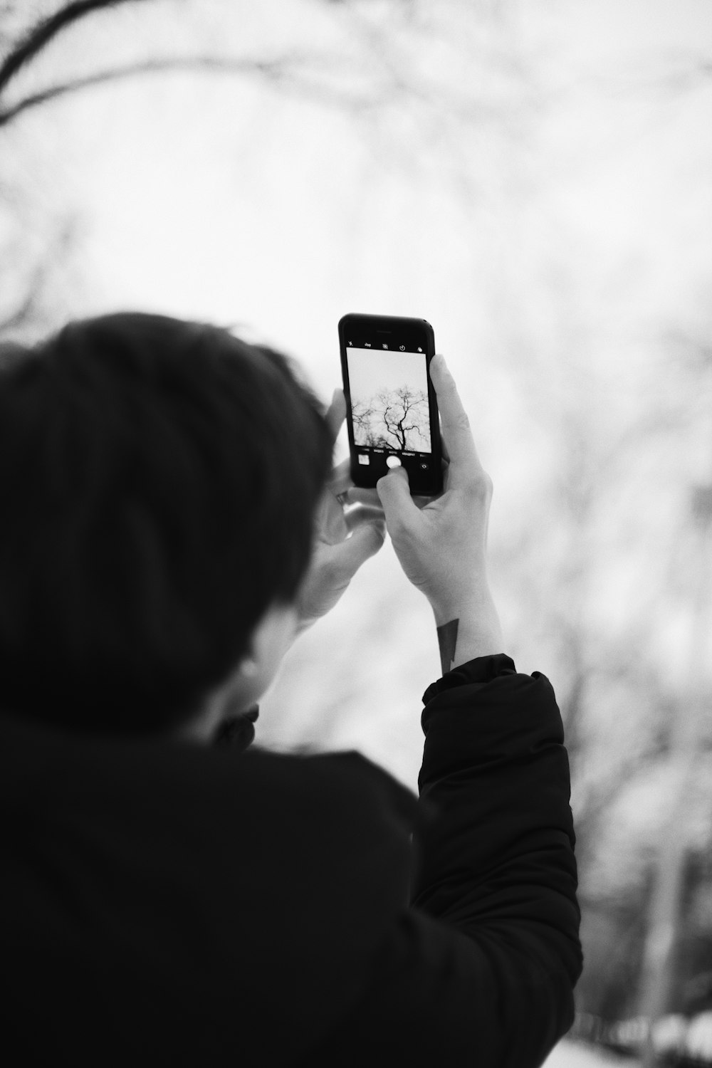 grayscale photo of man holding iphone