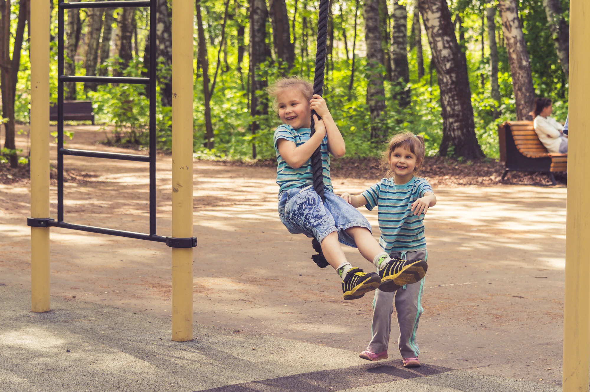 Two children laughing on swings in a park