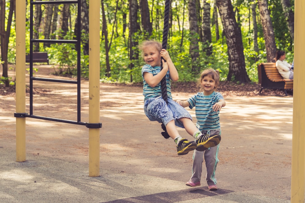 2 boys sitting on swing during daytime