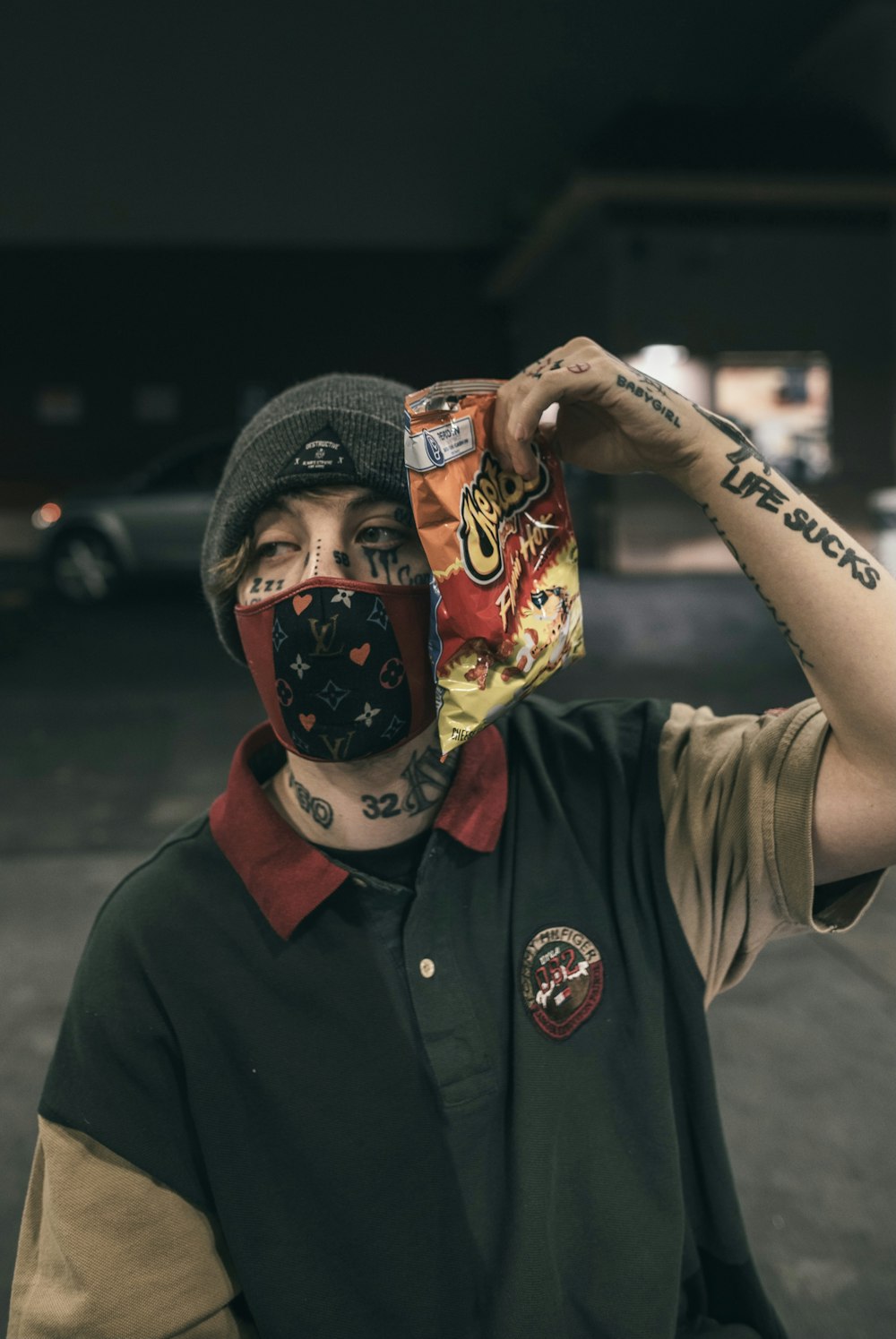 man in black button up shirt wearing black knit cap holding red and white mask