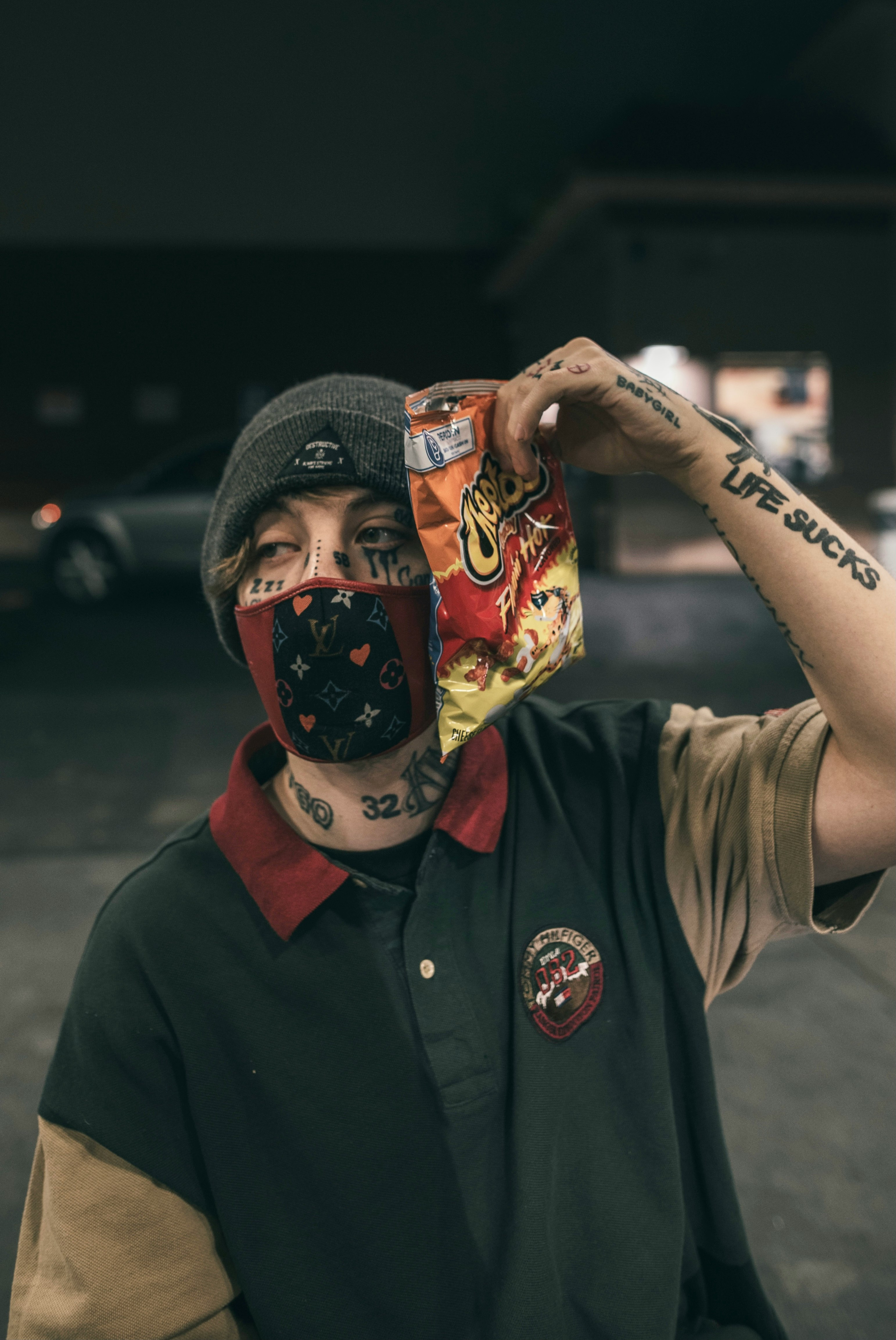 man in black button up shirt wearing black knit cap holding red and white mask