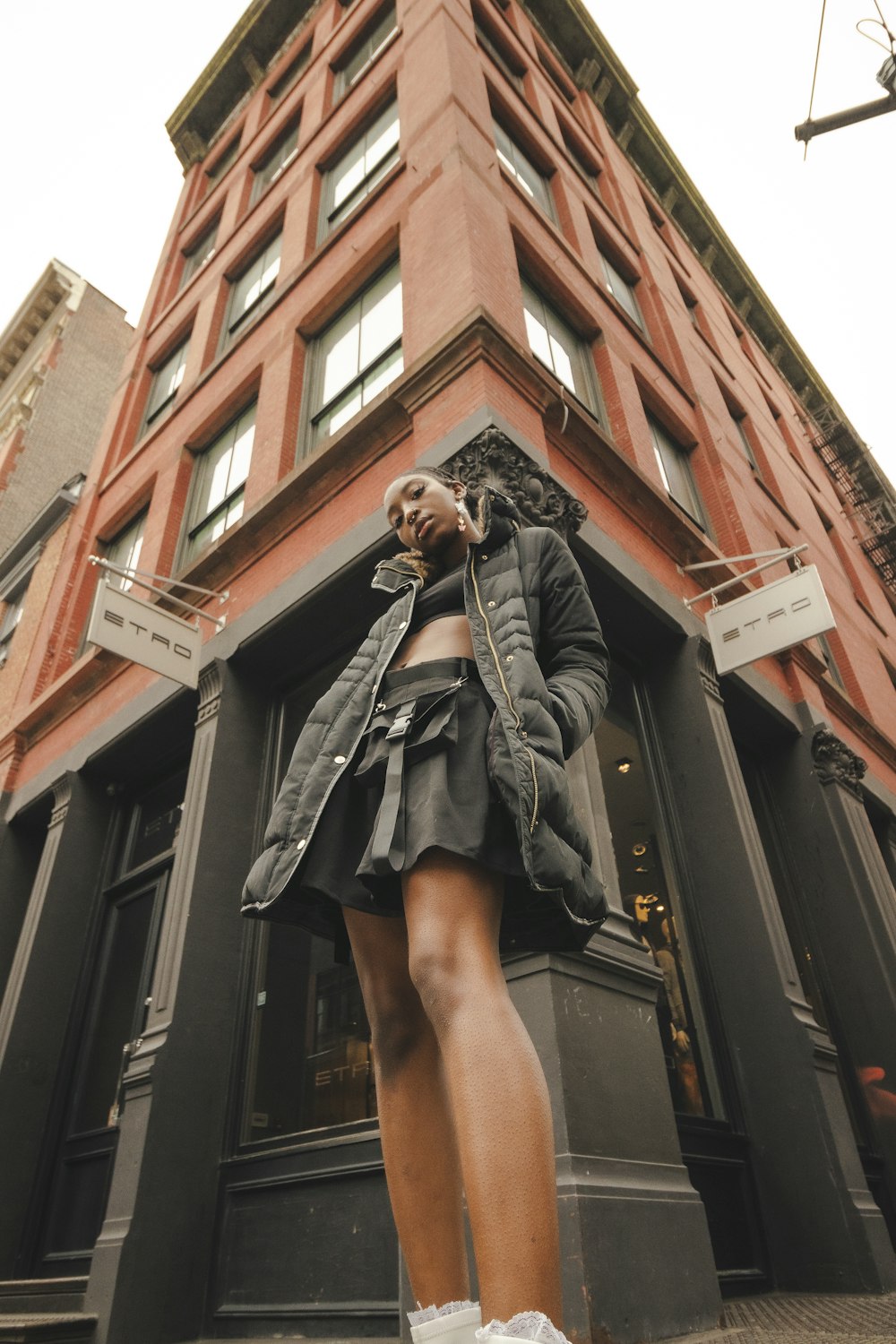 woman in black coat standing on brown concrete building during daytime