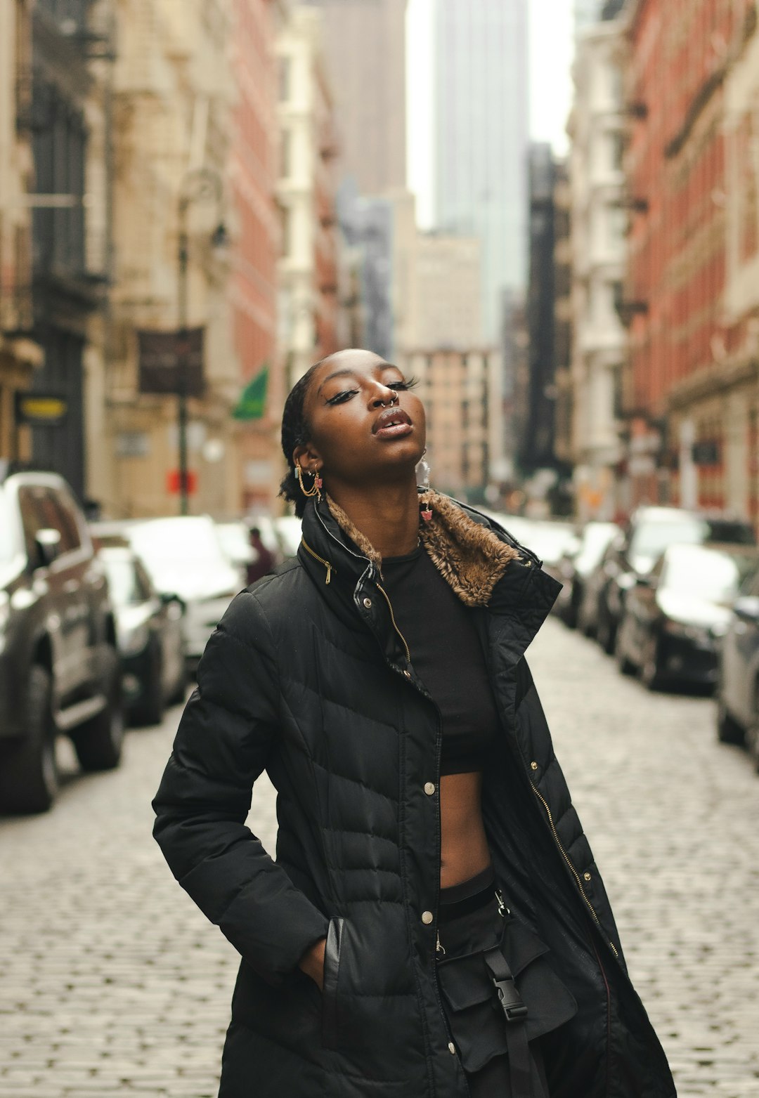 woman in black leather jacket standing on sidewalk during daytime