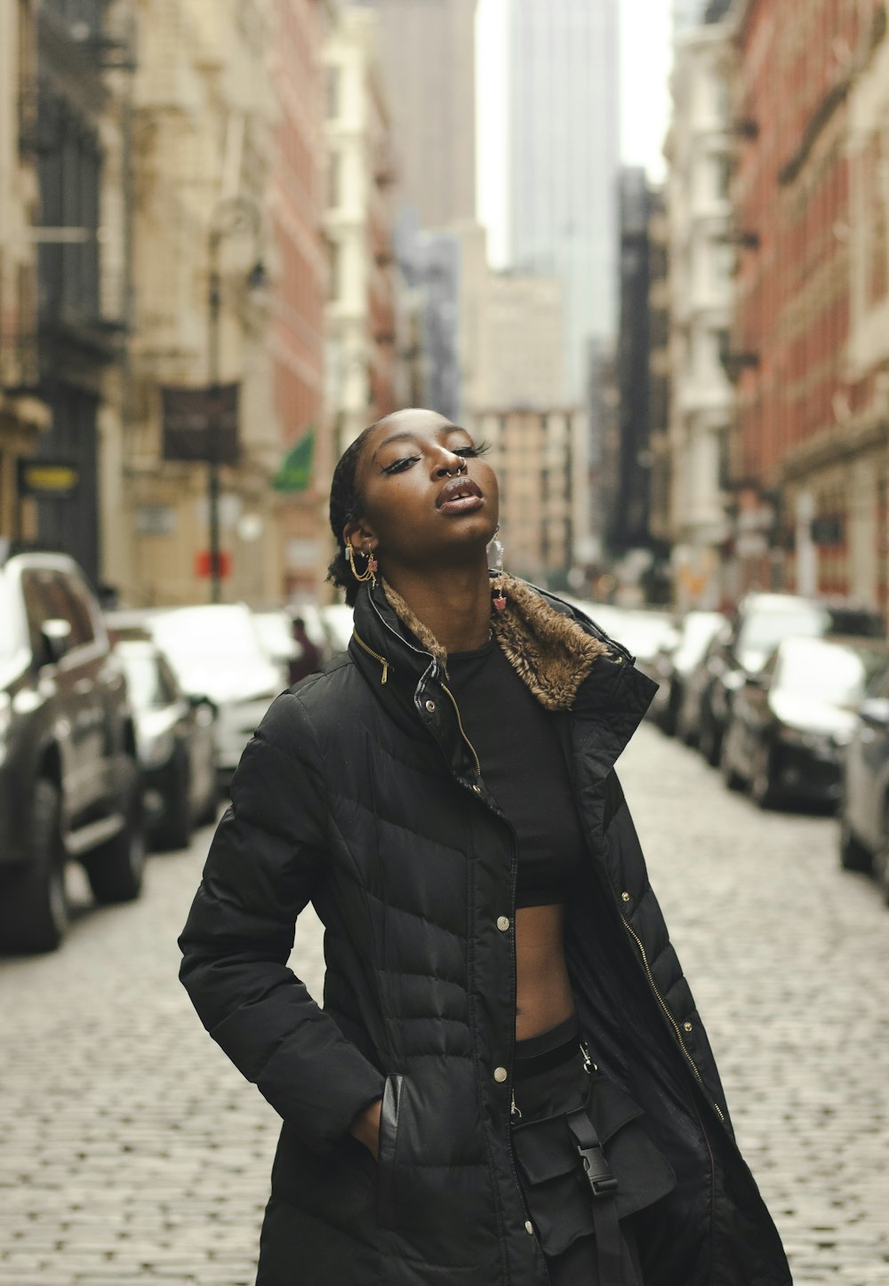 woman in black leather jacket standing on sidewalk during daytime