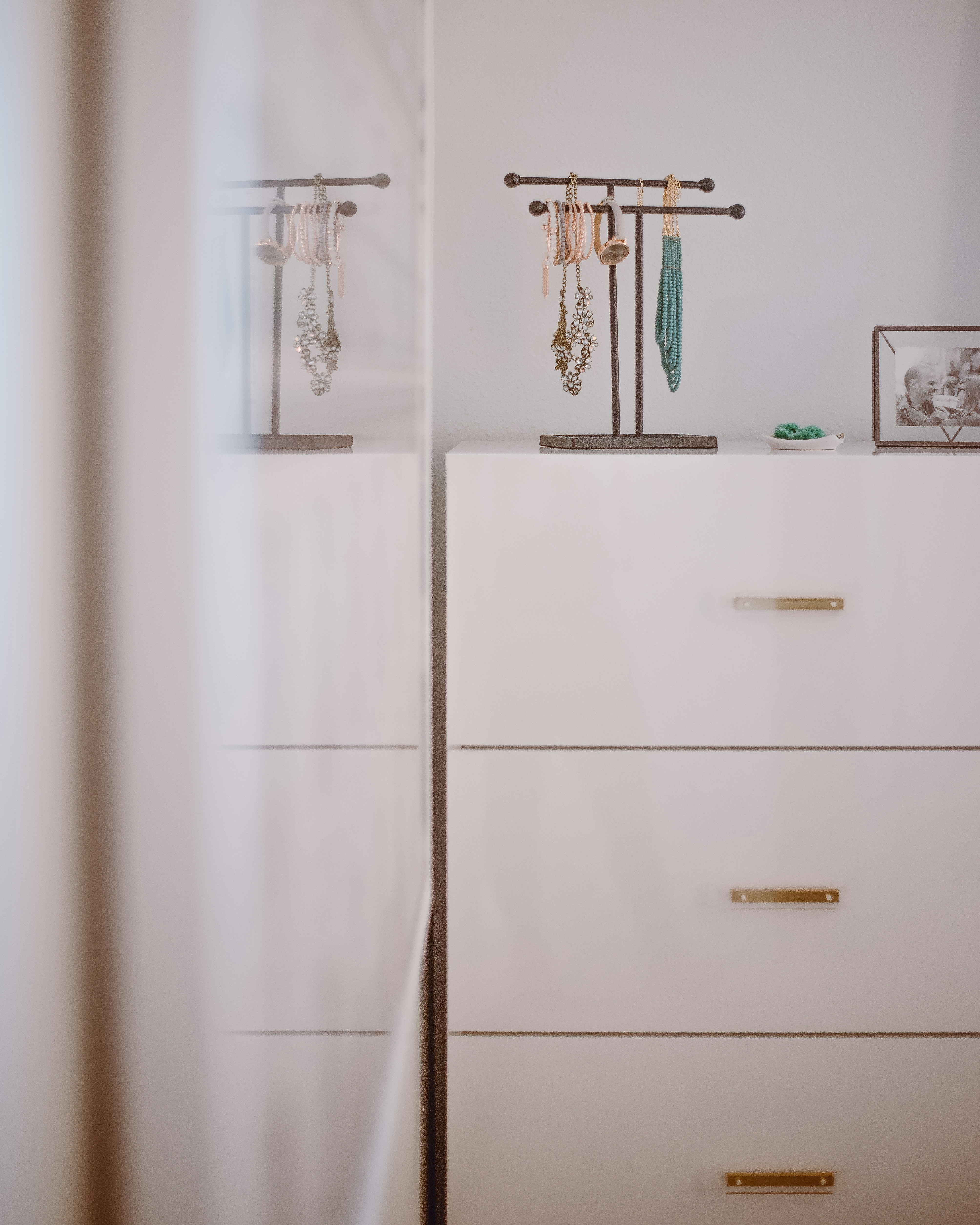 Jewelry hanging from organizer on top of white dresser