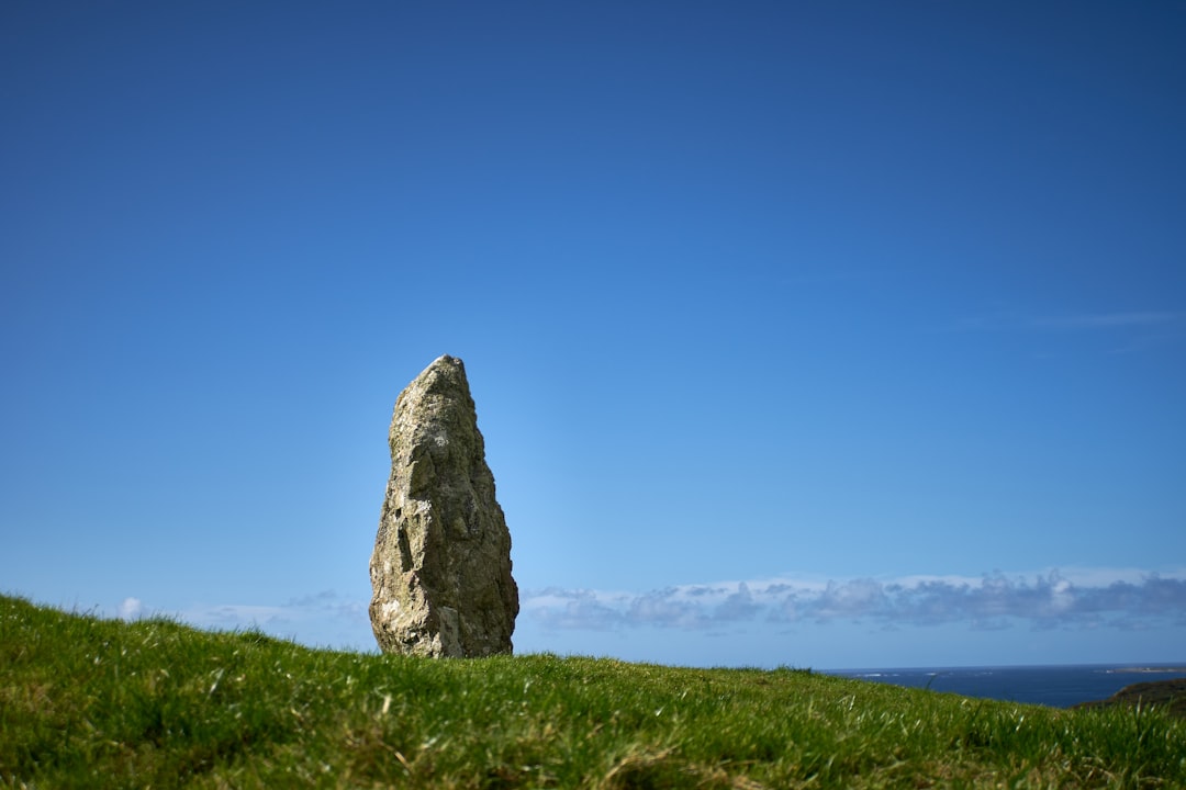 gray rock formation on green grass field under blue sky during daytime