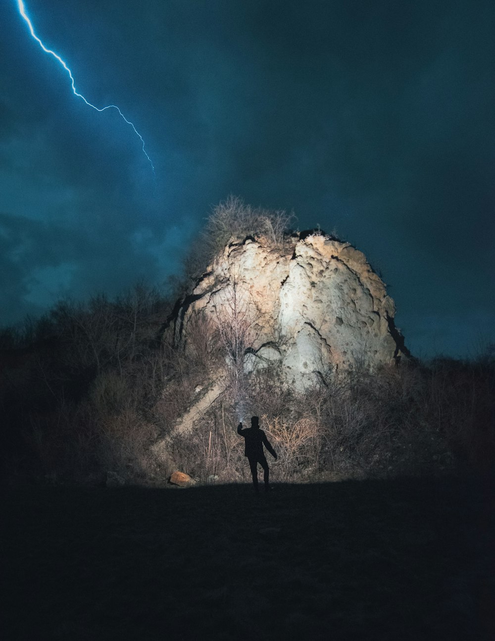 man standing near brown rock formation under blue sky during daytime