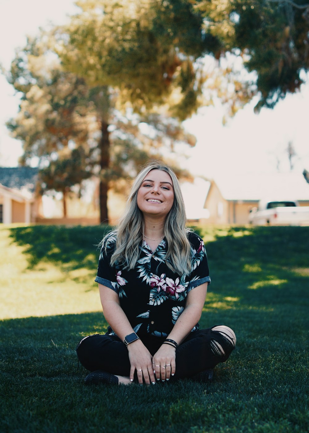 woman in black and white floral shirt sitting on green grass field during daytime