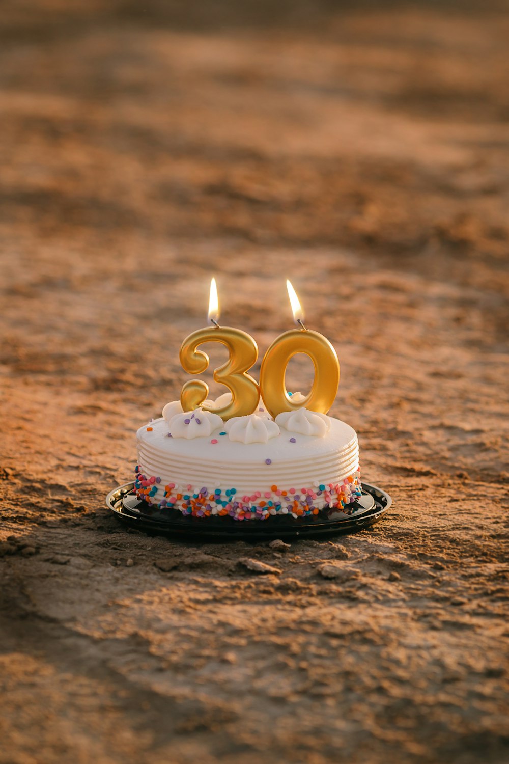 white and blue cake with candles on brown sand