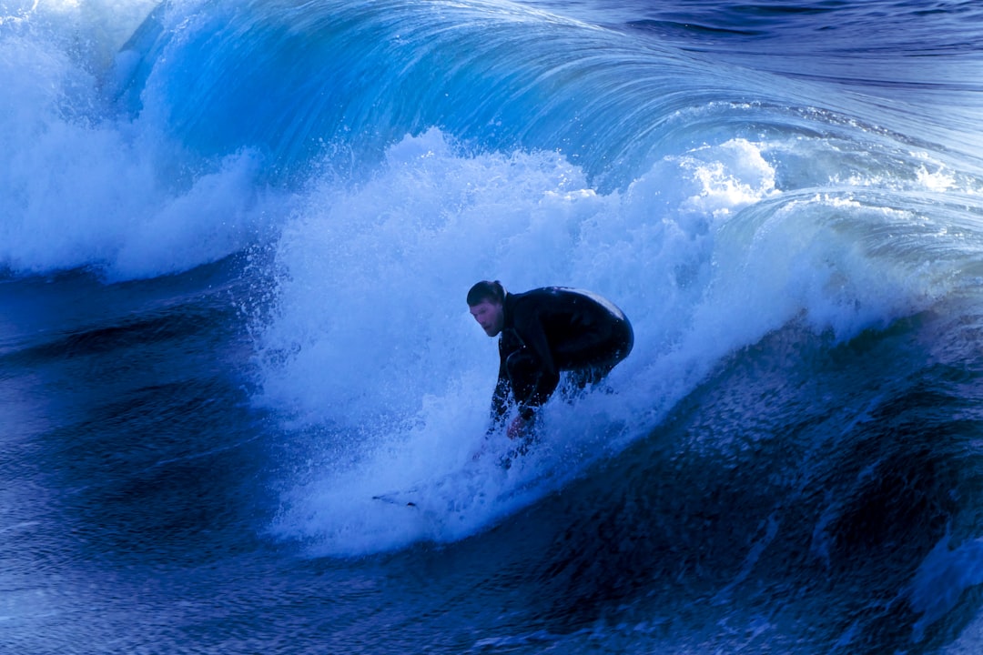 man in black wet suit surfing on blue ocean waves during daytime