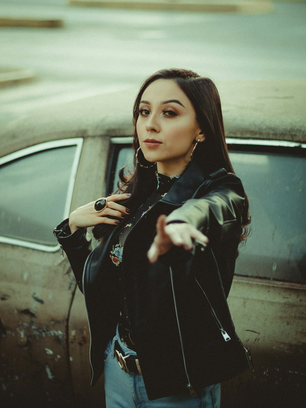 woman in black leather jacket standing beside black car during daytime