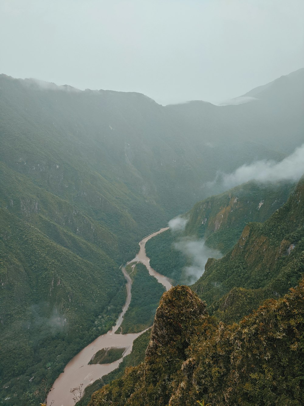 river between green mountains during daytime