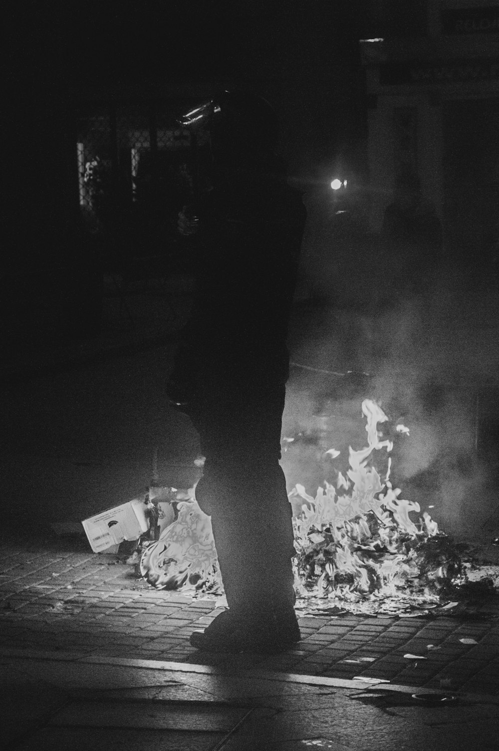 grayscale photo of man in black jacket and pants standing on road