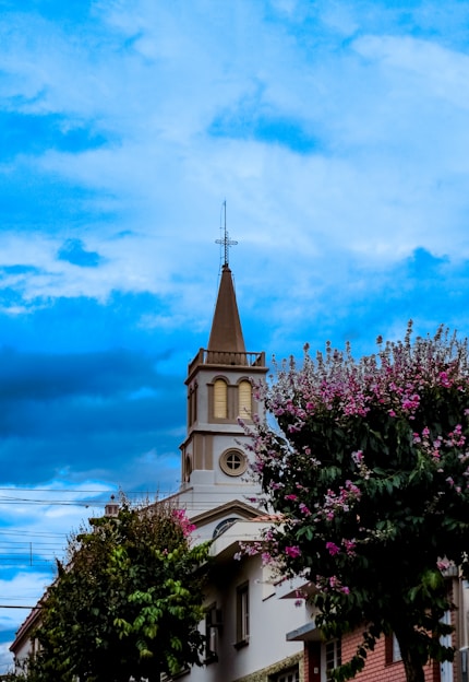 A vibrant scene of the CSI Holy Trinity Church adorned with maroon and gold floral decorations under a clear blue sky.