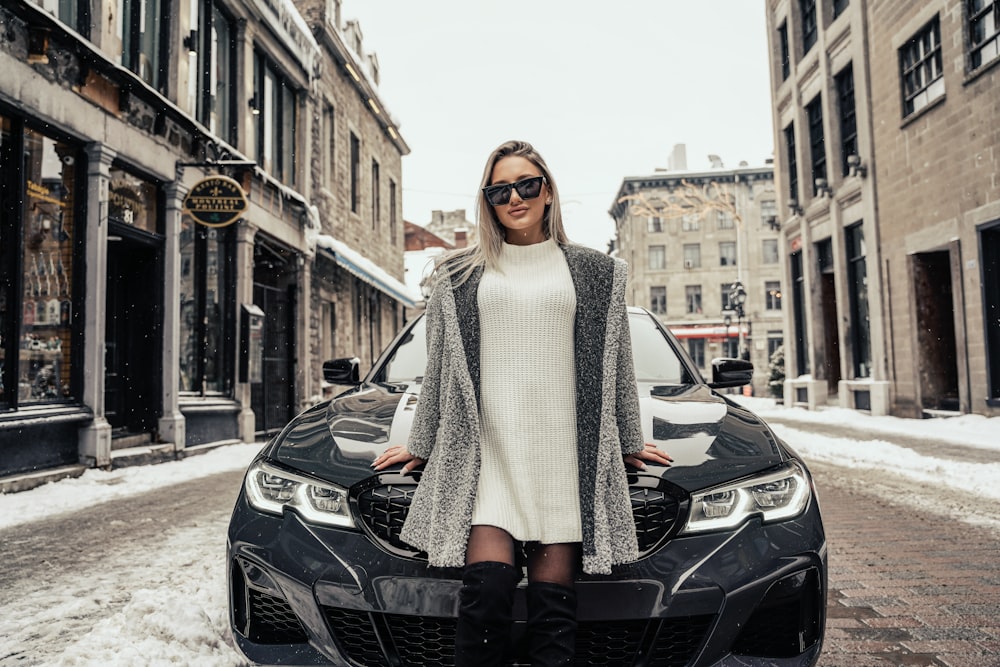 woman in white knit scarf standing beside black car during daytime