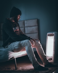 man in black hoodie and blue denim jeans sitting on white chair