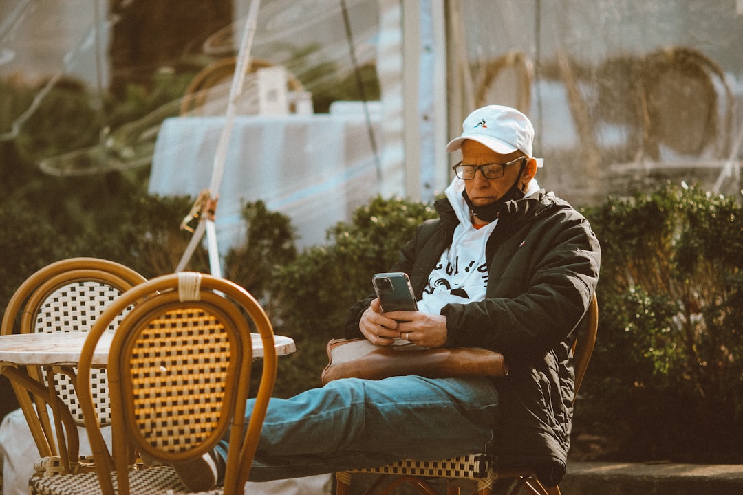 man in black jacket and white cap sitting on brown wooden armchair