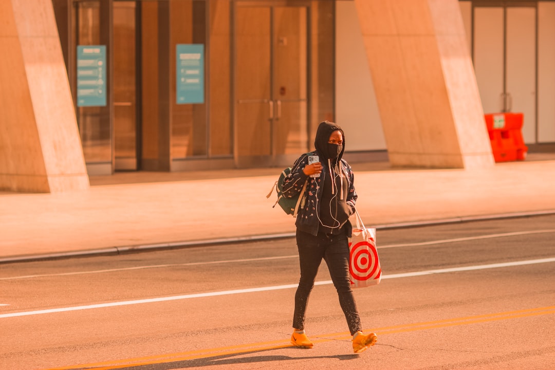 woman in black jacket and red pants walking on sidewalk during daytime