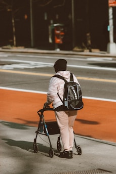 man in black and white jacket and brown pants with black backpack walking on road during