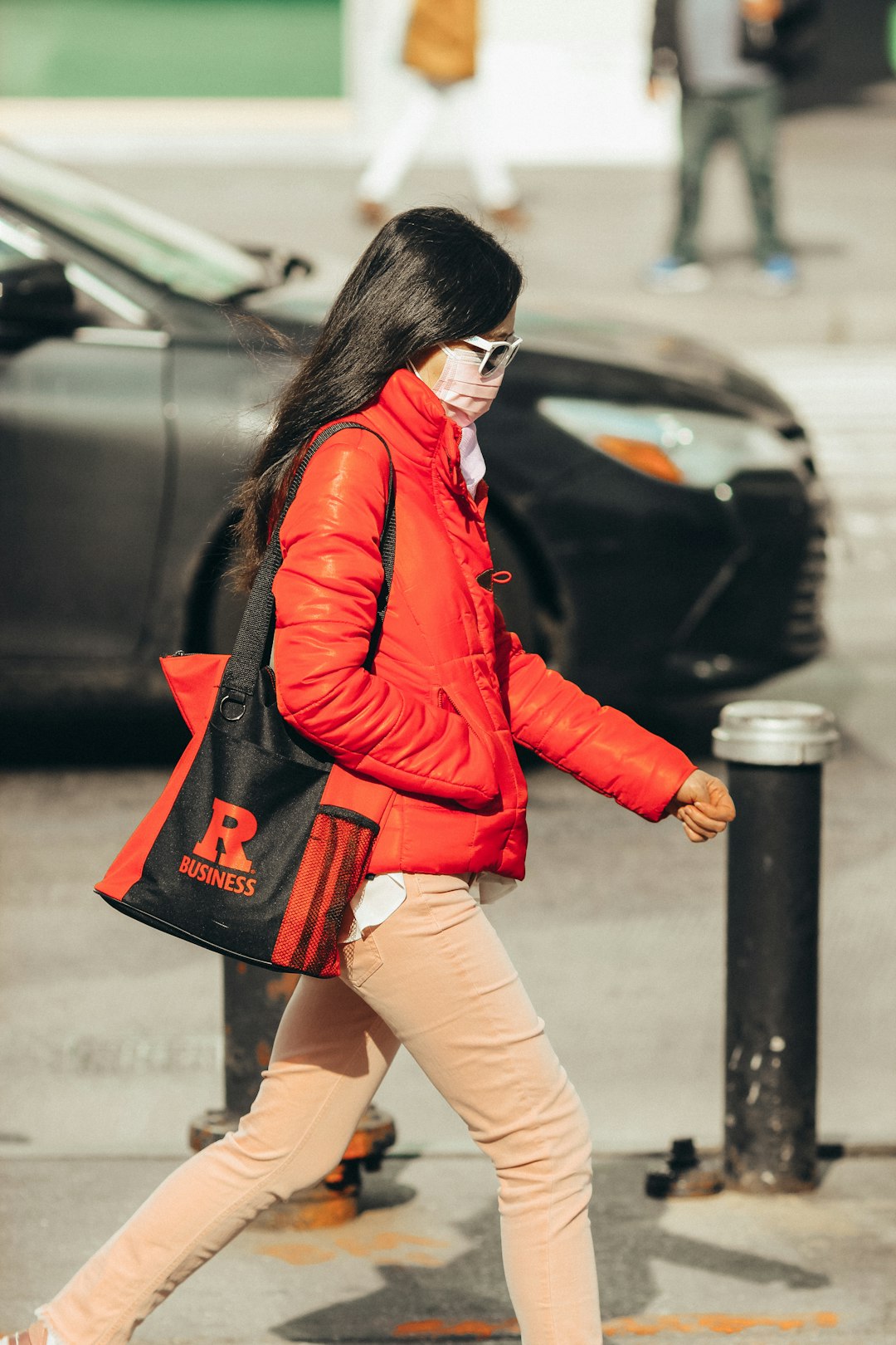 woman in red leather jacket and brown denim shorts standing beside black car during daytime