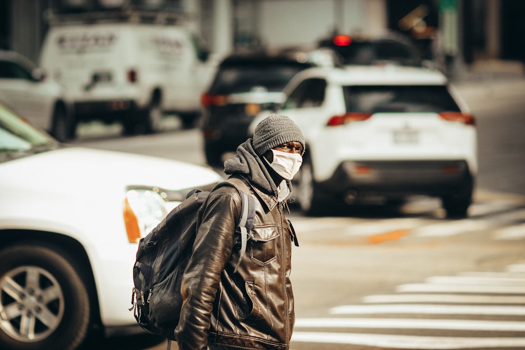 person in black leather jacket and white knit cap standing on street during daytime