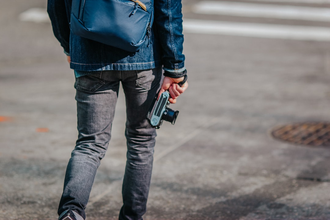 person in blue jacket and blue denim jeans holding black and silver dslr camera