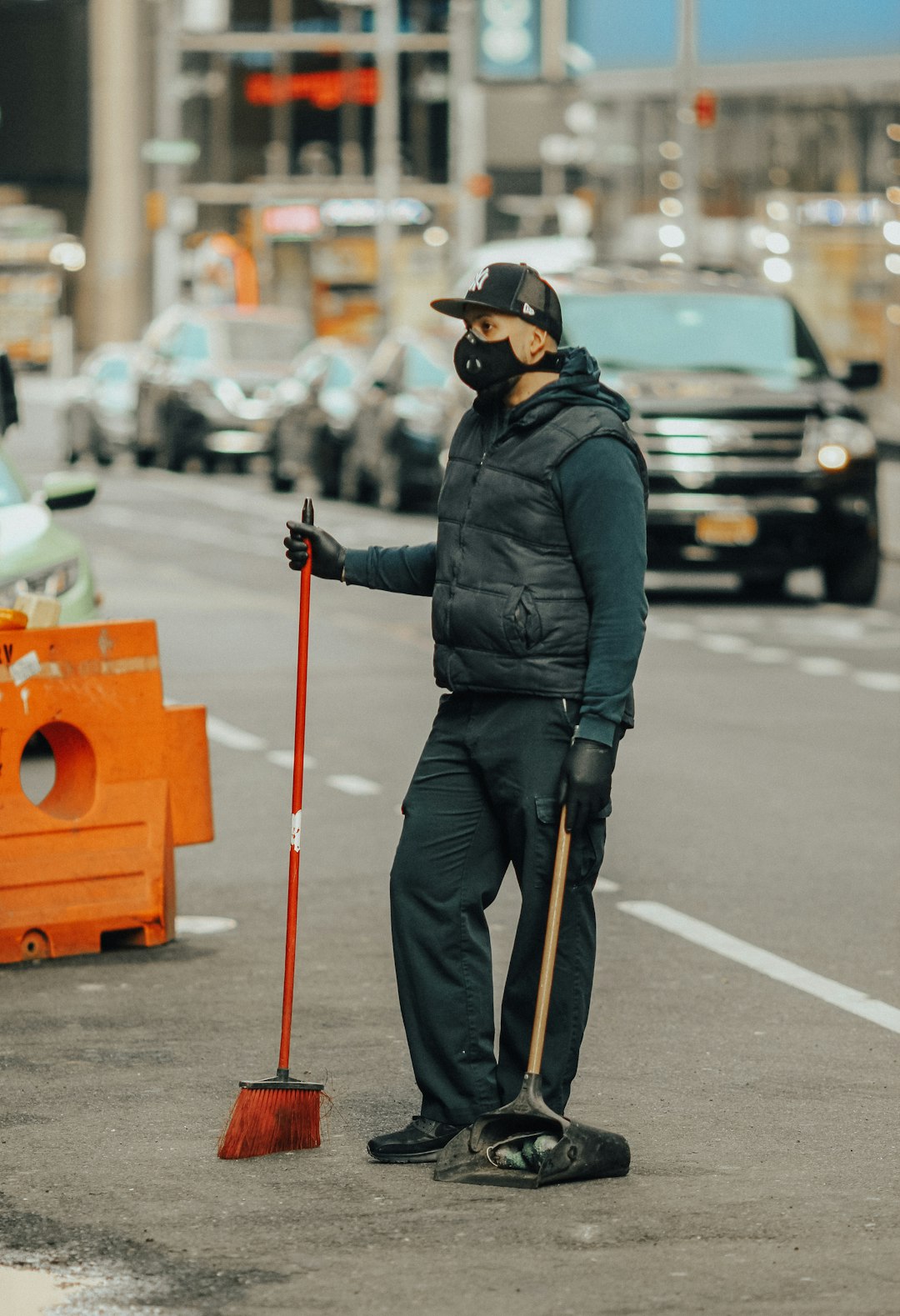 man in black jacket and black pants wearing black helmet holding red stick standing on road