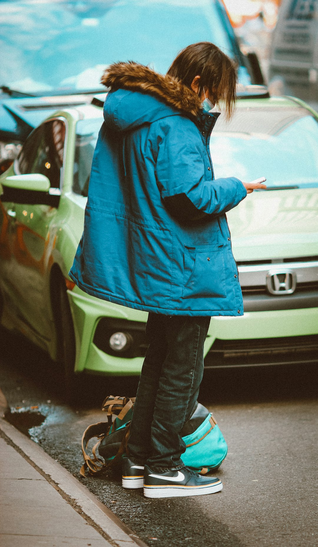 person in blue hoodie and black pants standing beside white car