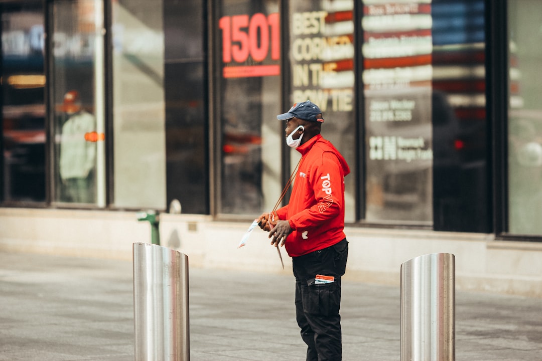 man in red hoodie and black pants holding black dslr camera