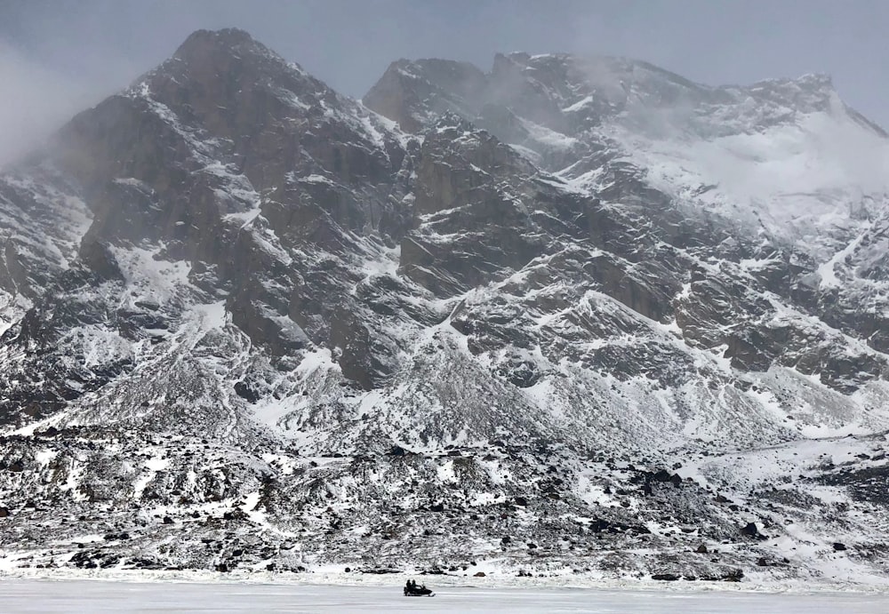 persone che camminano su un terreno innevato vicino a una montagna coperta di neve durante il giorno