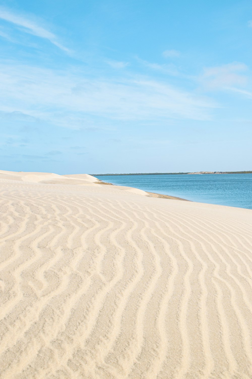 areia marrom perto do corpo de água durante o dia