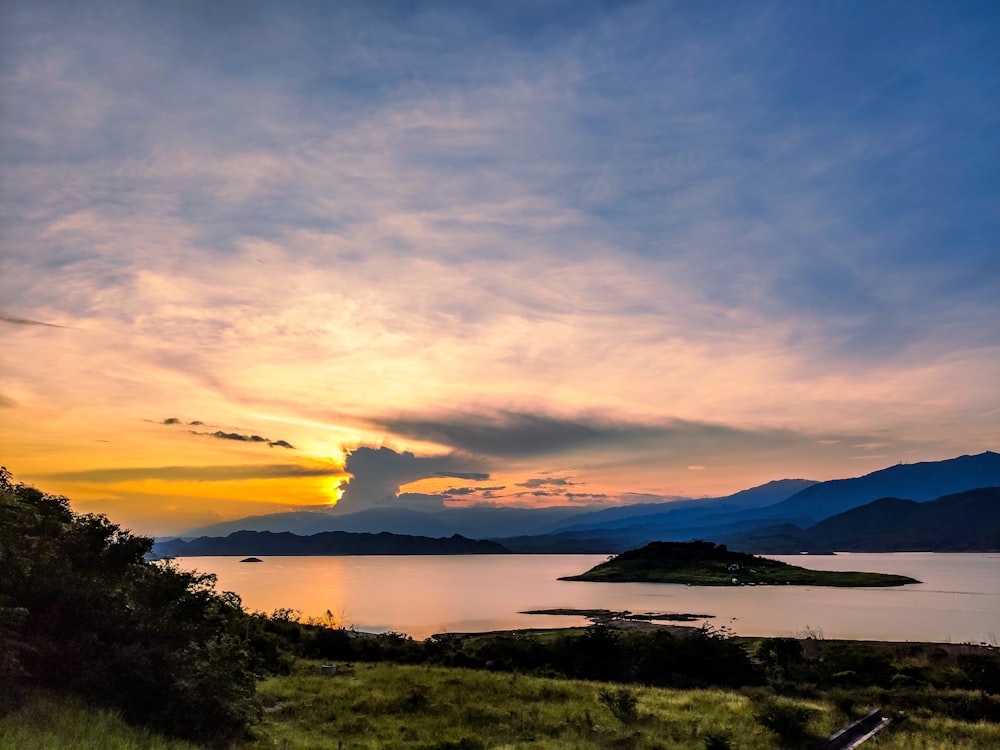 body of water near mountain during sunset