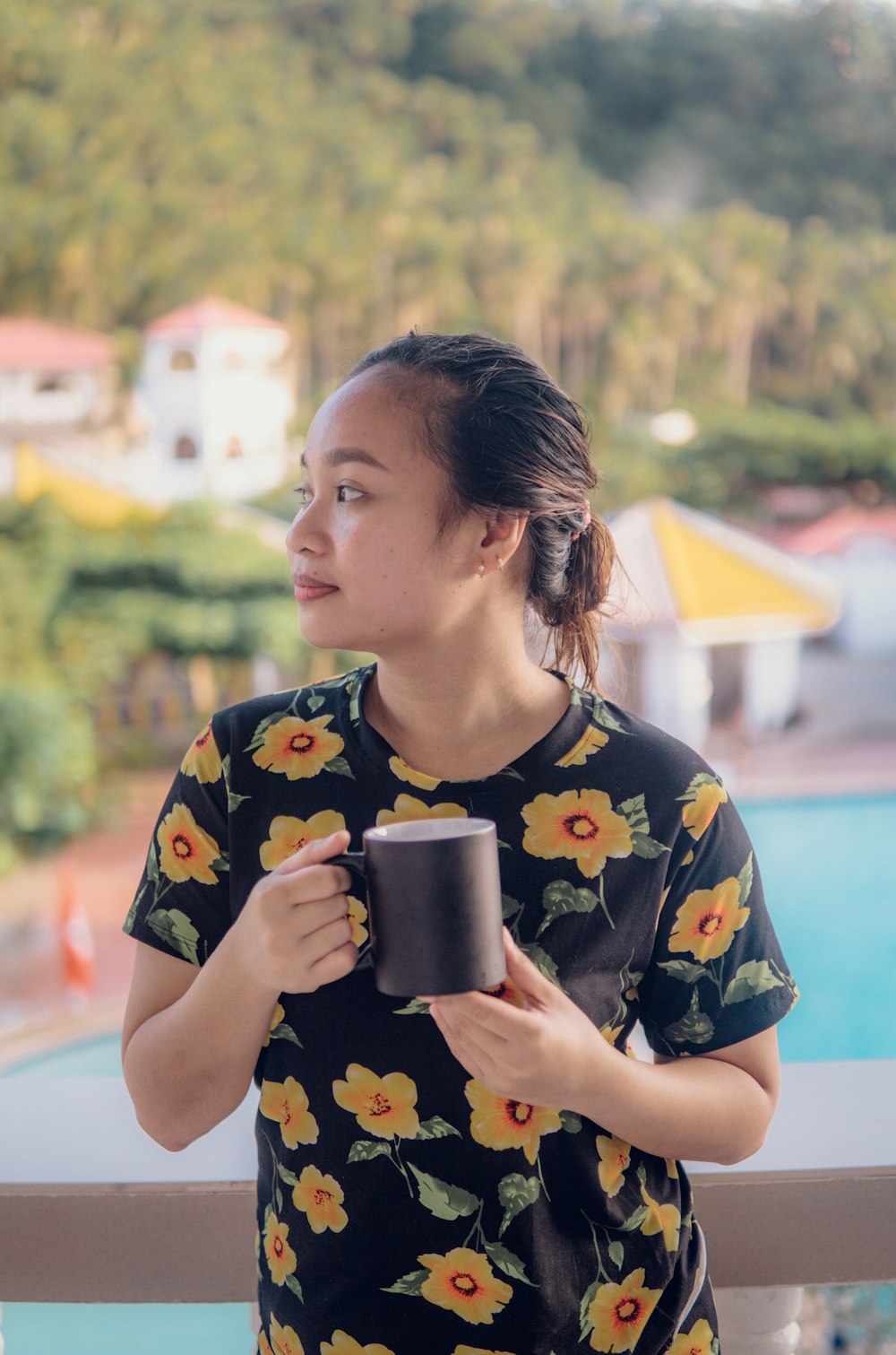 woman in black and yellow floral shirt holding cup