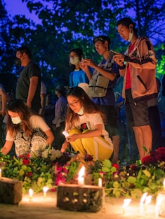 group of people standing in front of cake with candles