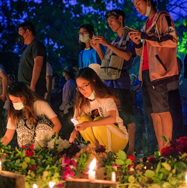 group of people standing in front of cake with candles