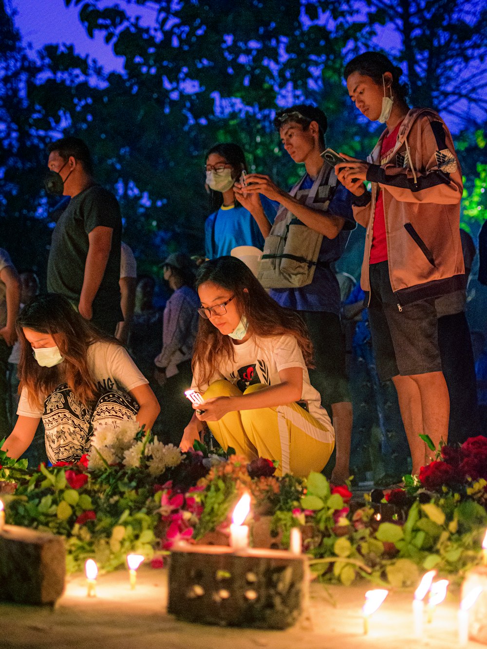 group of people standing in front of cake with candles