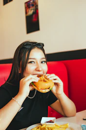 A smiling guest enjoying a loaded burger with fries on a rustic wooden table.