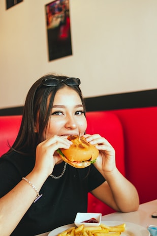 A customer enjoying a sandwich and fries with a big smile inside the cozy nk comida rapida restaurant.