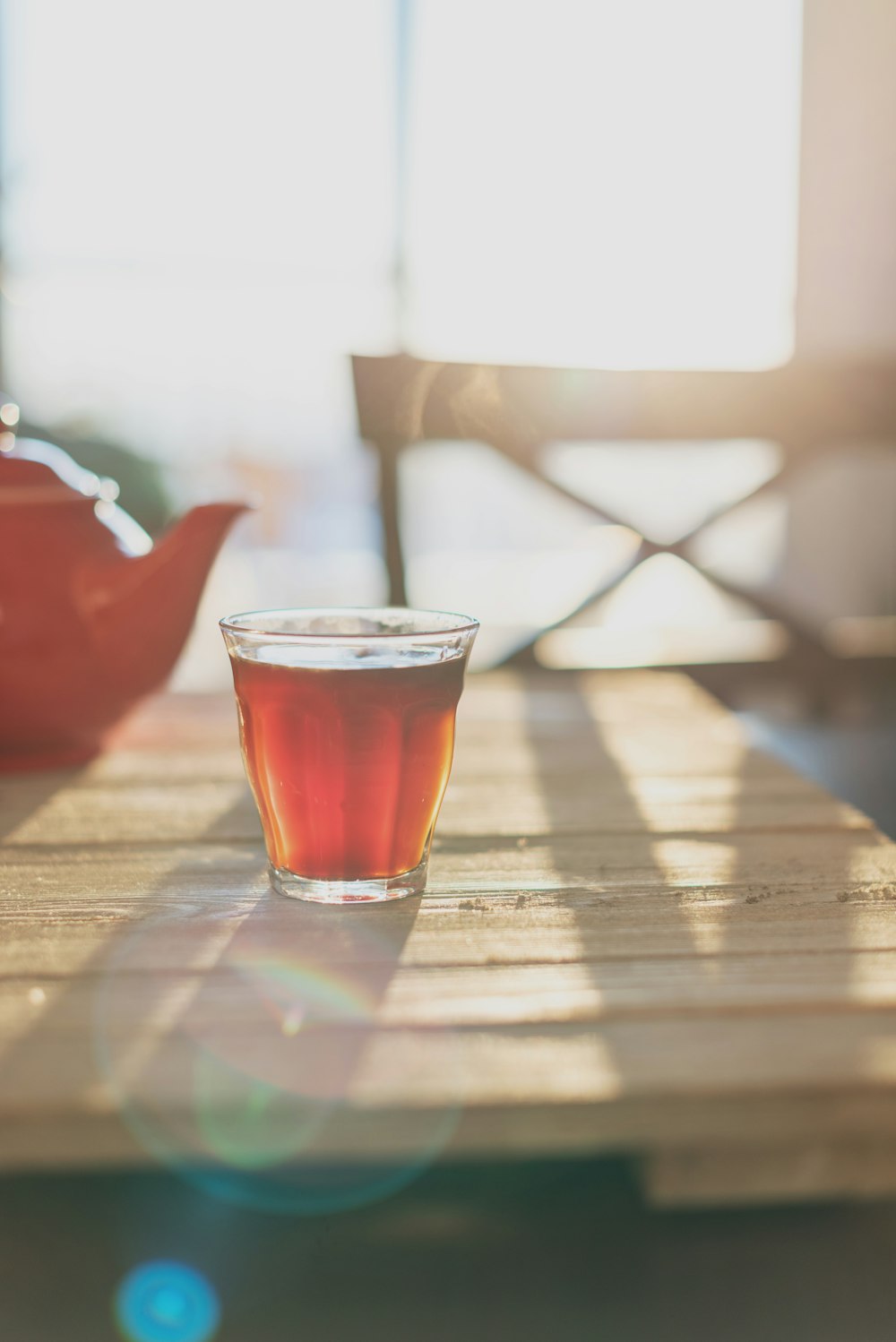 clear drinking glass with brown liquid on brown wooden table