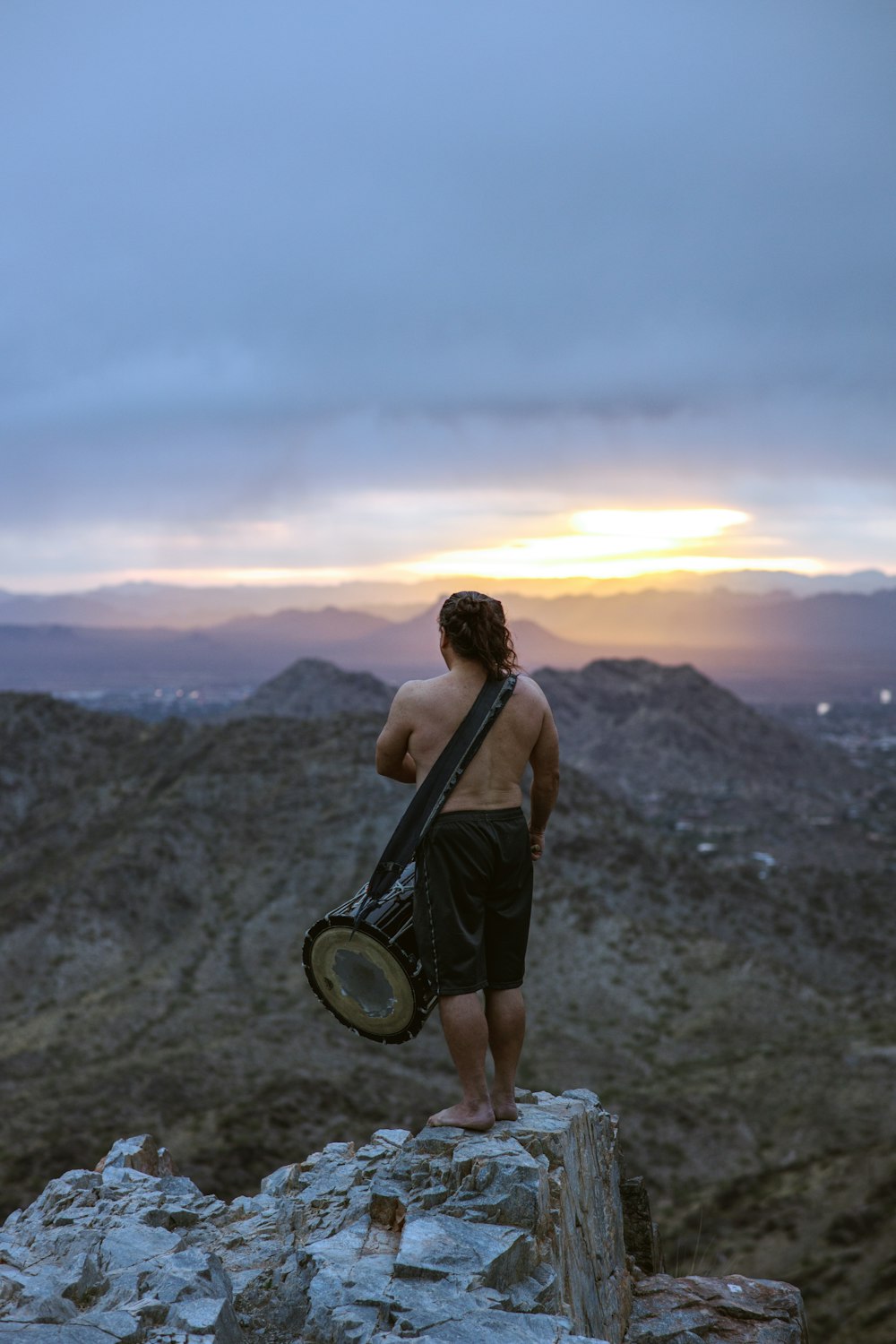 woman in brown tank top holding round mirror standing on gray rocky ground during sunset