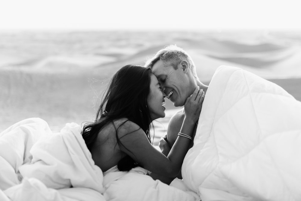 grayscale photo of couple kissing on beach