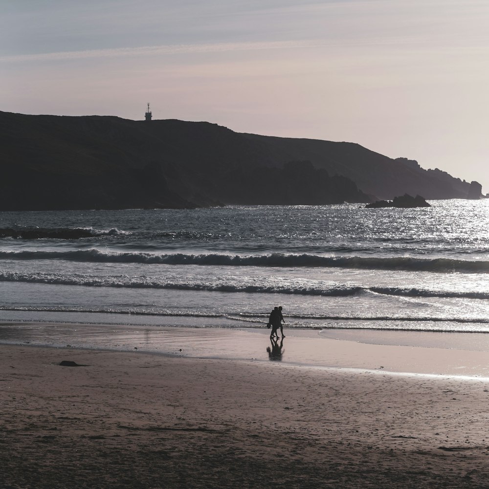 man in black jacket walking on seashore during daytime