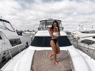 Aytac Kaptan standing confidently on the deck of a sleek yacht, ocean stretching behind him under a clear blue sky.