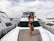 A stylish woman wearing premium jet ski eyewear standing confidently beside her jet ski in a luxury marina.